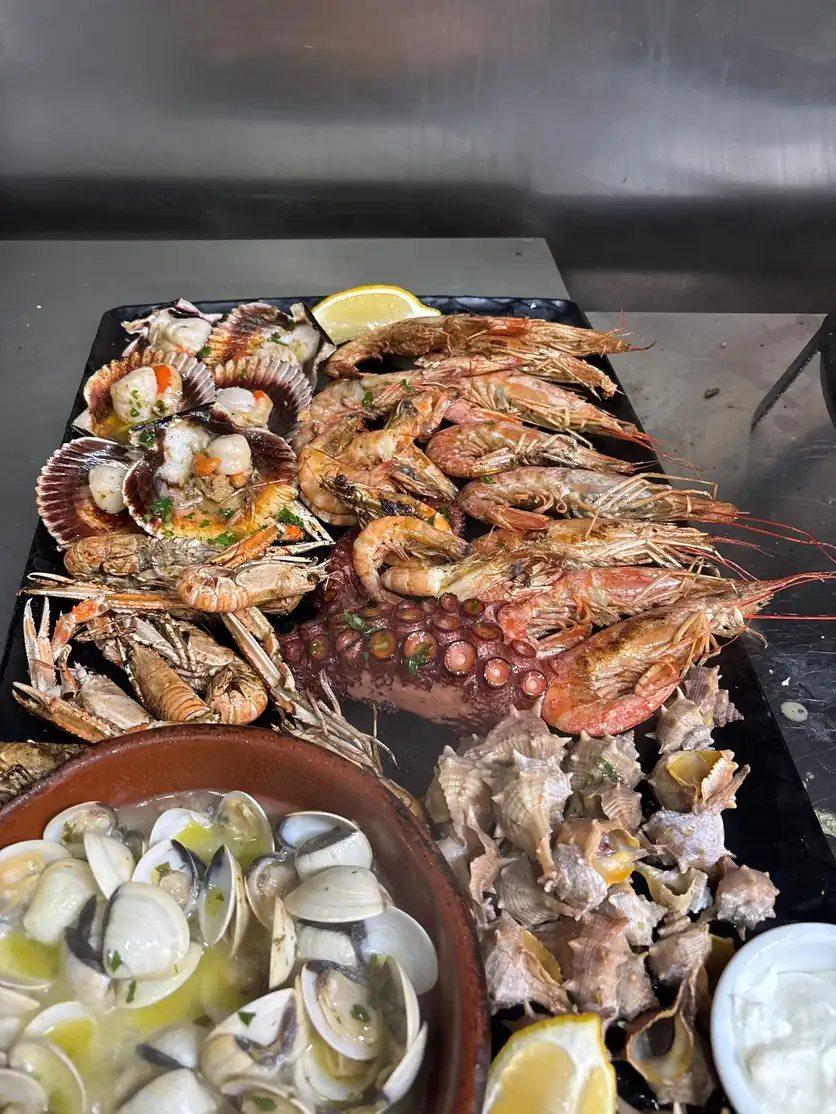 Parrillada de mariscos en Pulpería Arrocería el Poal, Vinaròs, con pulpo a la brasa y mariscos frescos, destacando la cocina mediterránea en primera línea de playa.